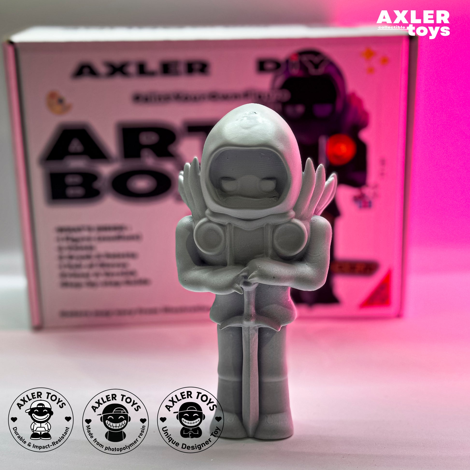 Toy figure of an astronaut in front of an Axler Toys Art Box with pink background