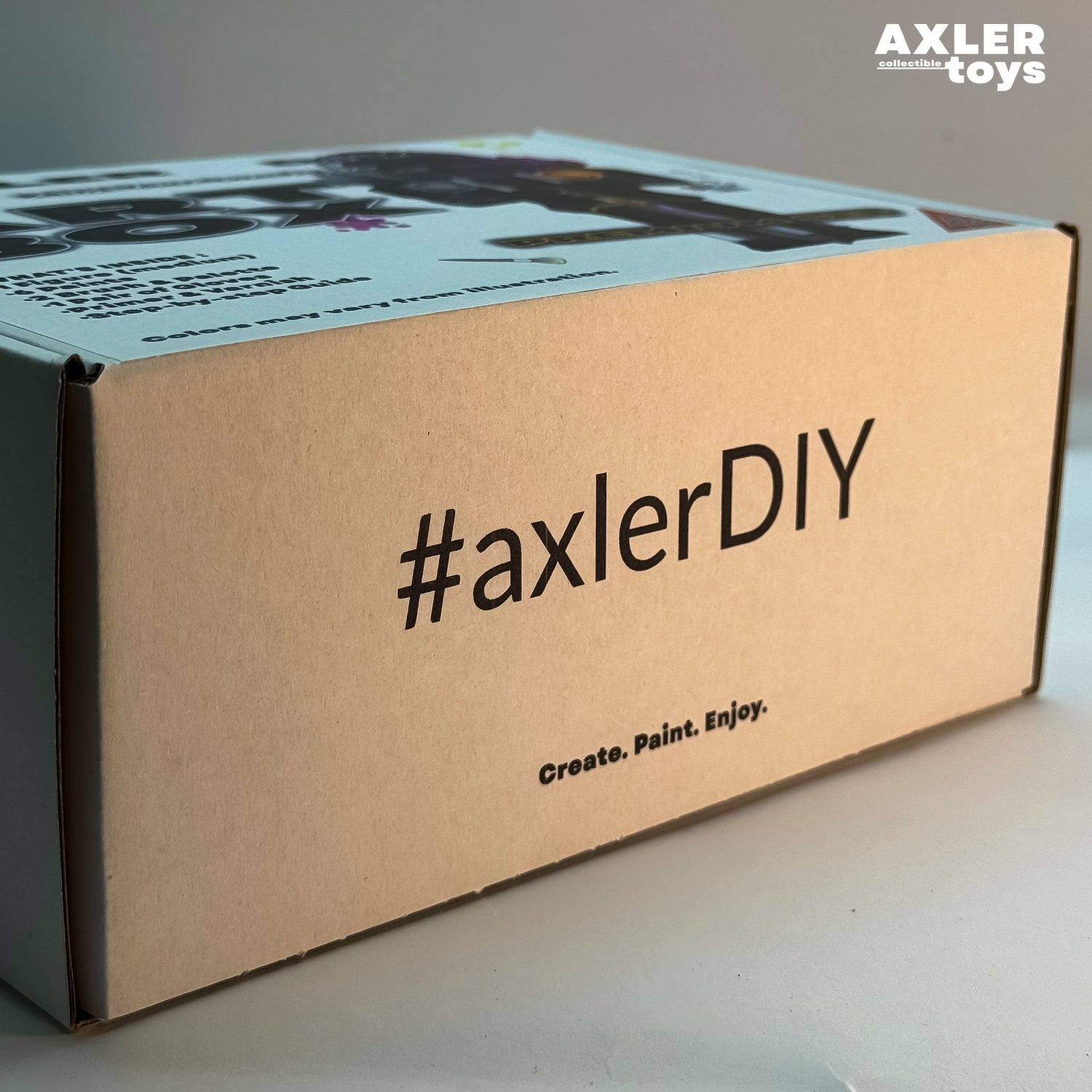 Cardboard box with '#axlerDIY' text and Axler Toys branding on a gray background